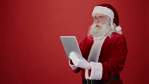 Santa Claus Reading Gift List on Tablet and Laughing