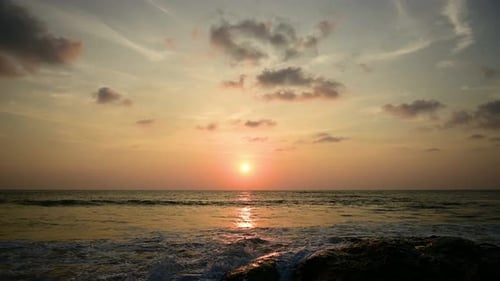 Timelapse of dramatic sunset with orange sky in a cloudy day at the ocean.