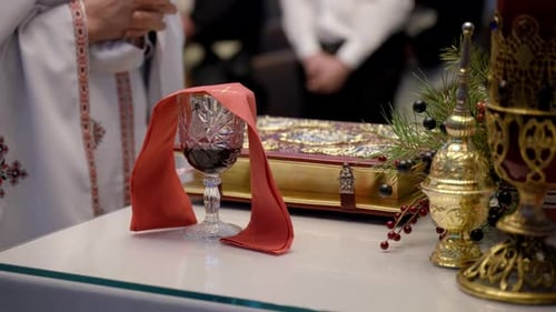 Der mit rotem Stoff bedeckte Heilige Kelch steht auf dem Kirchenaltar. Verschwommene Gläubige sind sichtbar in