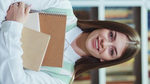Vertical Screen Cheerful Student Holding Books in Library