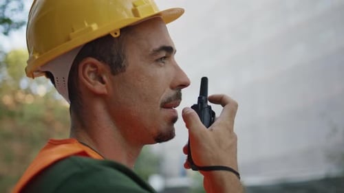 Der Chef spricht ein drahtloses Gerät in der Nähe der Stadt, der Walkietalkie benutzt