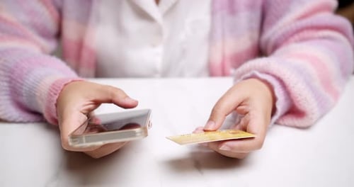 Close-up woman's hand holds a smartphone and use a mockup Bank credit card for online shopping servi