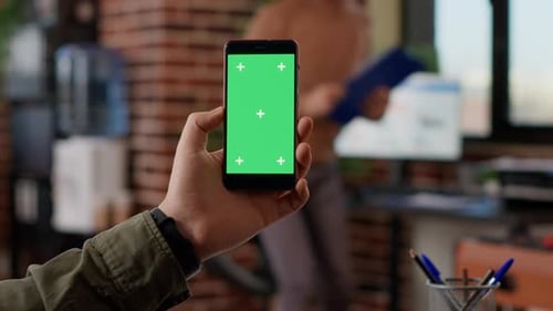 Hand Holding Phone with Green Screen in Office