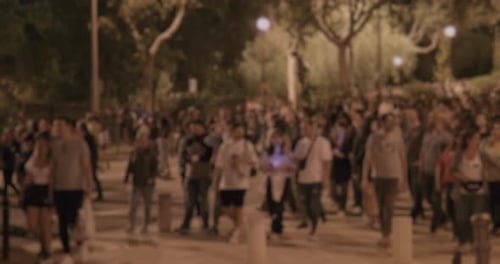 Blurred Crowd Walking on Bright Sidewalk at Night