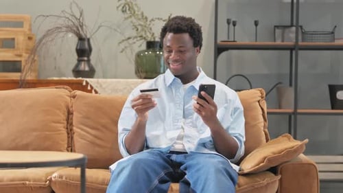 Young Adult Shopping Online with Credit Card on Couch