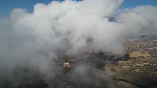 Aerial view of a quaint small town, nestled amidst clouds, painted in the hues of a stunning sunset.