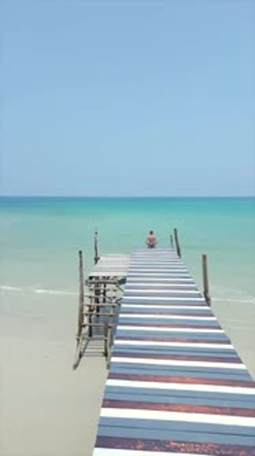 Woman Walks Along Wodden Pier on Paradise Beach with Crystal Clear Turquoise Sea