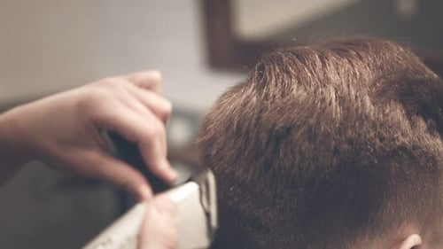 Nahaufnahme eines Friseurs beim Haarschnitt eines Mannes mit einem Elektrorasierer im Friseurladen