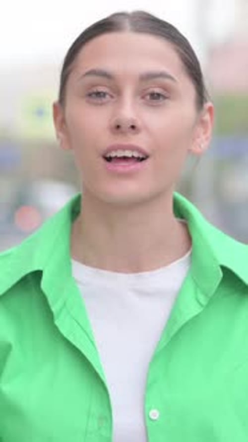 Smiling Woman in Green Shirt Waving and Talking