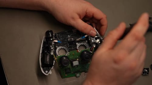 Technician Hands Using Screwdriver Working on Gaming Controller Revealing Delicate Electronic