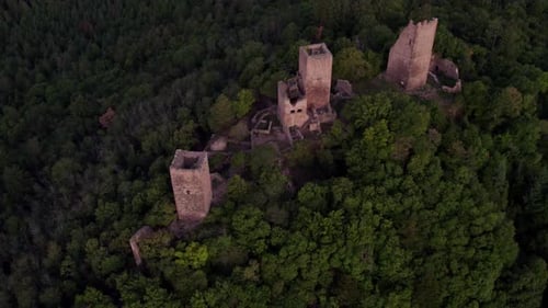 Aerial view of castle ruins in dense forest, France.