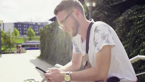Portrait of a Handsome Guy Standing in the Park with Phone