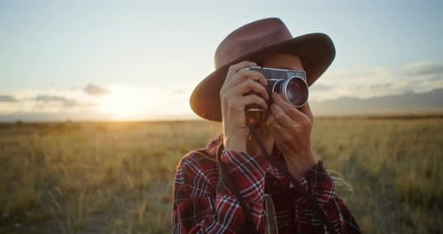 Photographer Taking Pictures with Vintage Camera in a Field at Sunset