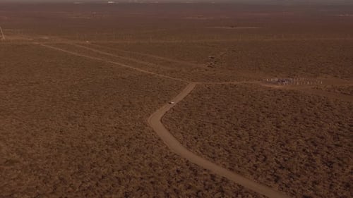 Aerial Shot of Lonely Car Traveling Through Desert Landscape