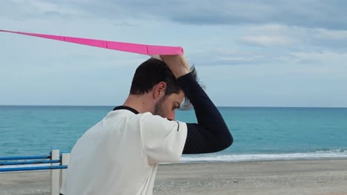 Young Adult Stretching with Resistance Band on Beach