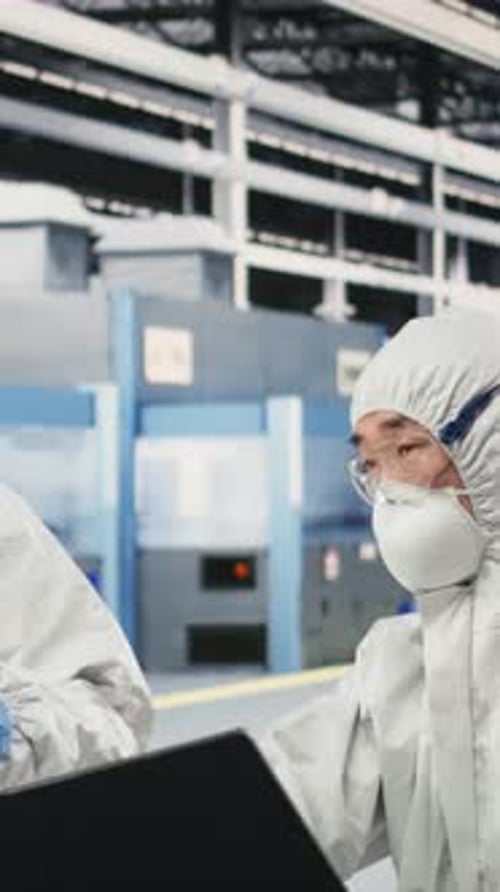 Vertical Video Engineering Team Working Together in Semiconductor Production Plant Floor