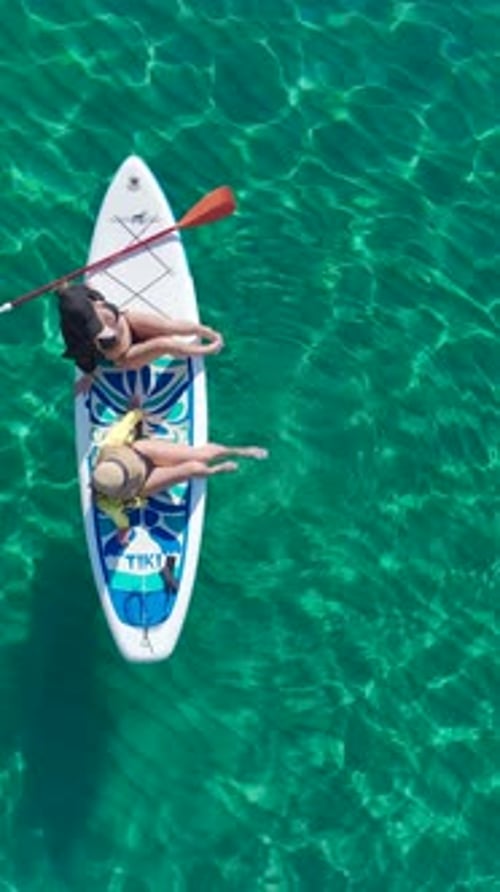 Vertical Video Paddleboard Adventure on Crystal Waters with Models Posing and Swimming in Style