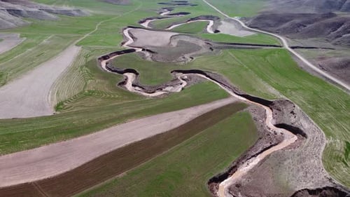 Luftaufnahme des Flusses, der durch die Felder im riesigen Land fließt 4K