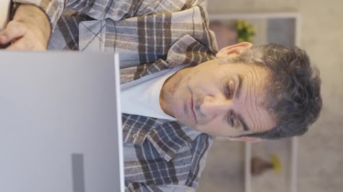 Vertical Video of Mature man working in home office talking to himself about his work.