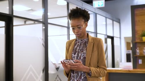 Businesswoman Checks Phone in Office Corridor