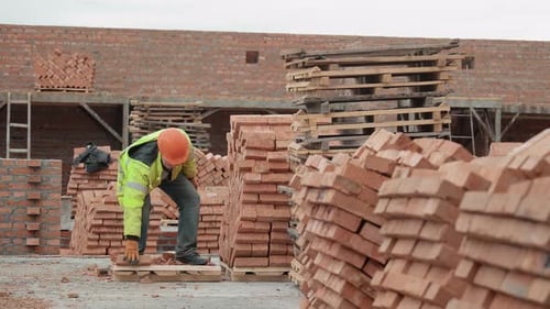 Construction Worker Organizing Brick Stacks at a Building Site Worker in Safety Gear Arranging