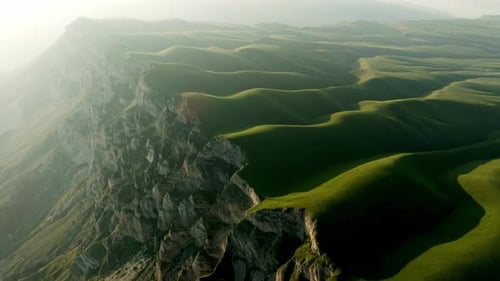 A Majetic Mountain Looms Over a Misty Highland Its Rocky Cliff Contrasting Against the Vibrant Green