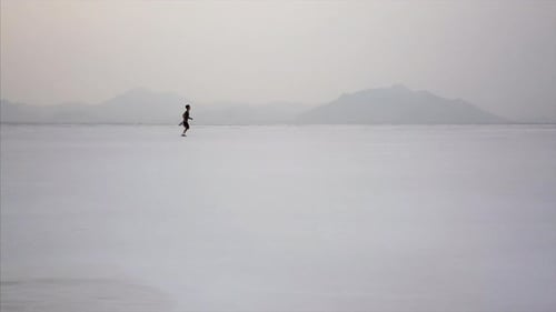 Dramatic aerial of boy running in desert Utah salt flat