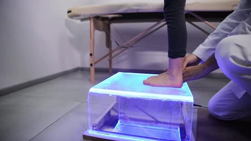 Medical Professional Examining Child's Foot on Illuminated Platform