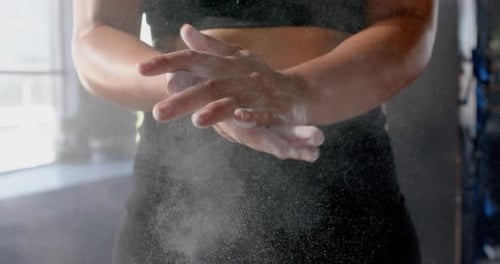 Clapping hands with chalk dust, woman preparing for workout in gym
