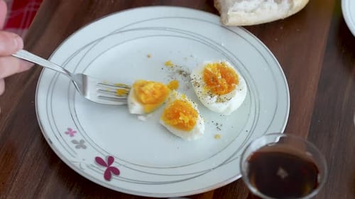 Close-up of Person Cutting Hard Boiled Egg with Fork on Plate