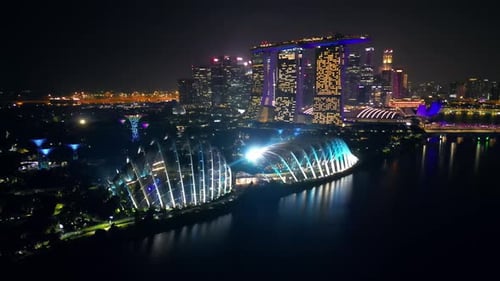 Aerial drone view of Singapore's Marina Bay skyline at night featuring Marina Bay Sands, the ArtScie