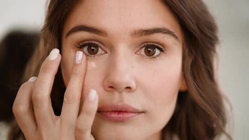 Woman Applying Concealer Underneath Eye in Close Up