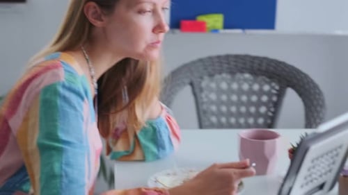 Woman Enjoys Meal While Browsing on Her Tablet Casual Scene of Woman Eating and Watching Tablet at