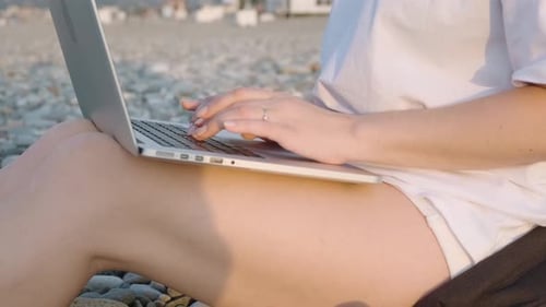 Close Up of Caucasian Gir Working with Laptop Typing on Computer Keyboard on the Beach By the Sea