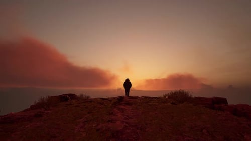 Hiker Silhouette Standing on Cliff at Dramatic Sunset