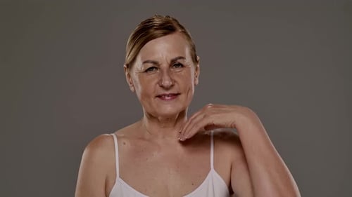 Mature Woman Touching Face and Neck in Studio