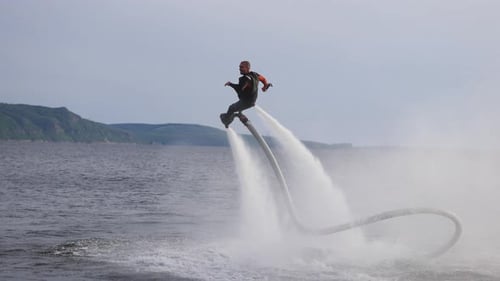 El flyboard es un nuevo deporte extremo en el que un alegre flyboarder masculino vuela sobre el agua y actúa