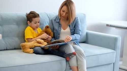 Woman Reads to Child with Teddy Bear on Sofa