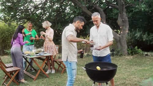 Two Men Adult Friends Cooking Barbecue and Drinking Beer Preparing Garden Meal