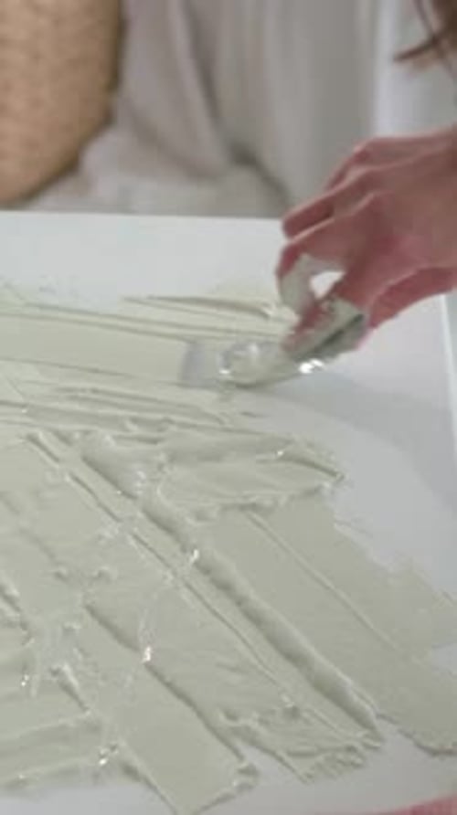 Vidéo verticale : Artiste ramassant de la pâte et étalant avec un couteau à palette, apprêtant la toile pour la peinture