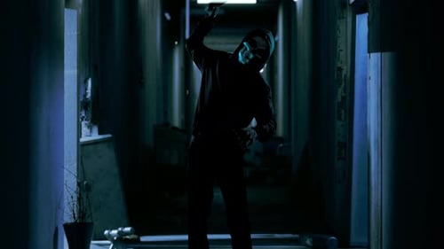 Hooded Figure in Mask in Dark Hallway