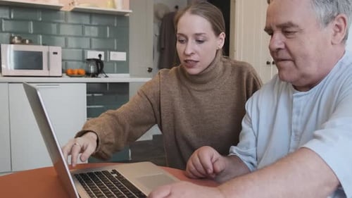 Caring Daughter Teaching Elderly Father How to Use Laptop Showing How to Typing on Computer in