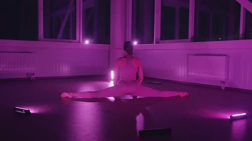 Ein junges Mädchen in Top und Leggings streckt sich im Fitnessraum und sitzt auf einer Querseite