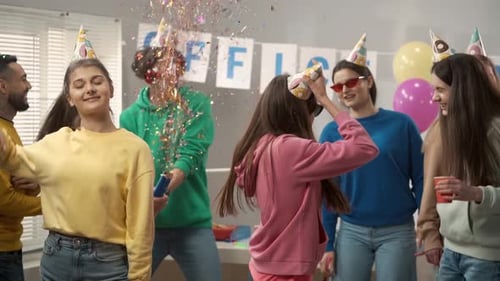 A Group of Colleagues in Festive Hats and Glasses are Dancing Having Fun Celebrating a Common