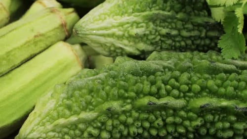Une gourde amère, un légume souvent utilisé comme ingrédient en cuisine, est posée sur une table en bois.