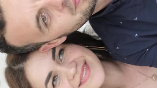 The Husband and Wife are Sitting on the Couch They Smile and Take Pictures on Their Phone