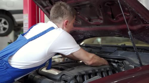 Mechaniker in blauer Uniform repariert Automotor führt Diagnosetests durch Fahrzeugwartung im Auto