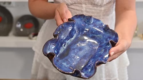 Woman Holds and Rotates a Blue Ceramic Bowl