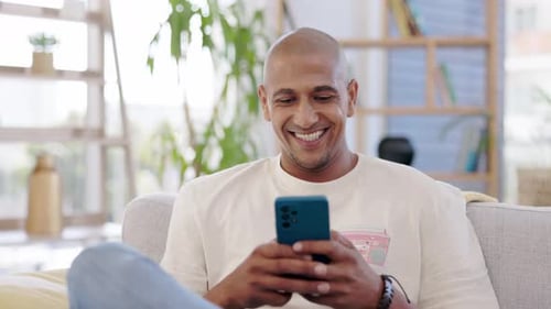 Man Smiling While Using Smartphone Indoors