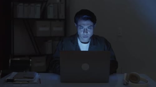 Serious Software Developer Working on Laptop Late at Night